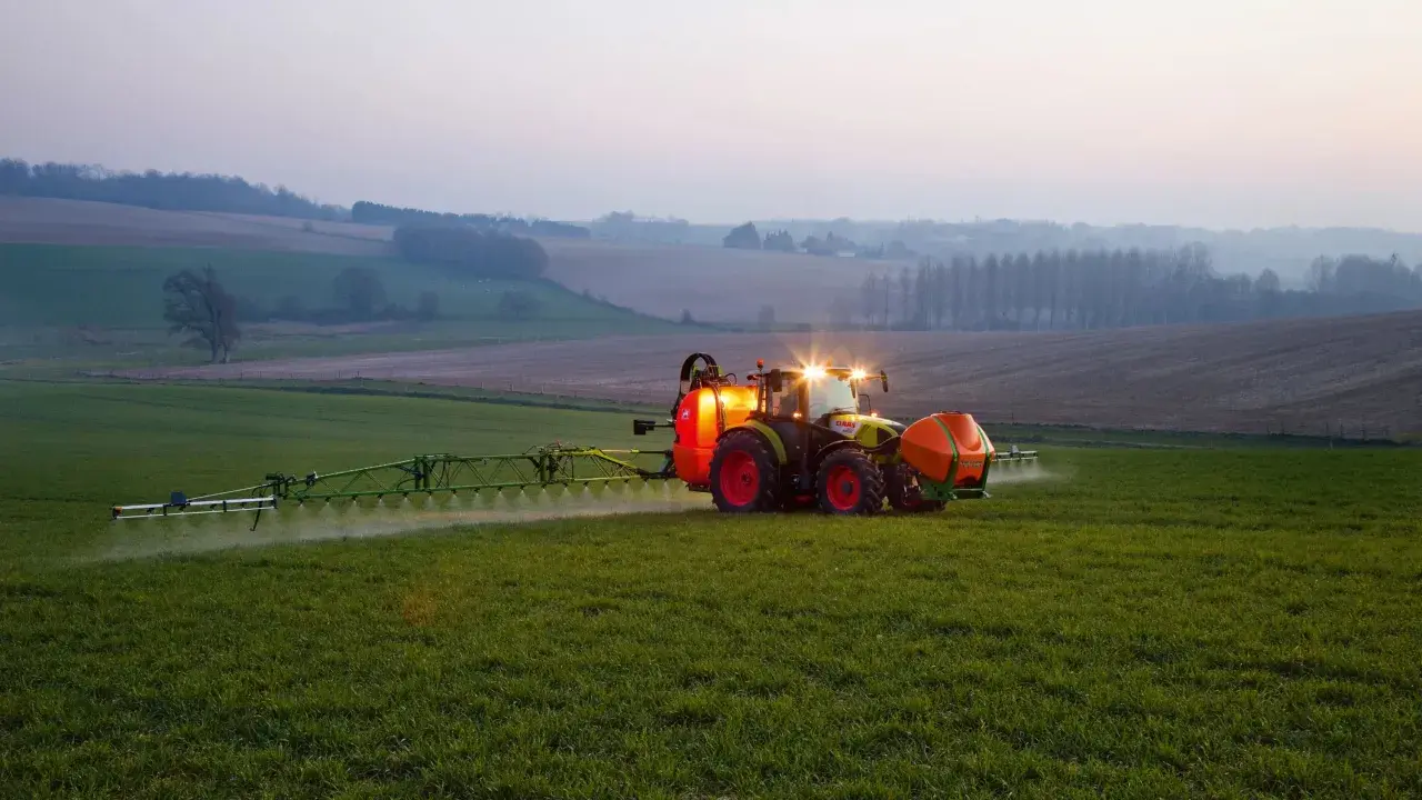 Ciągnik z opryskiwaczem na polu, precyzyjne dawkowanie roundup.