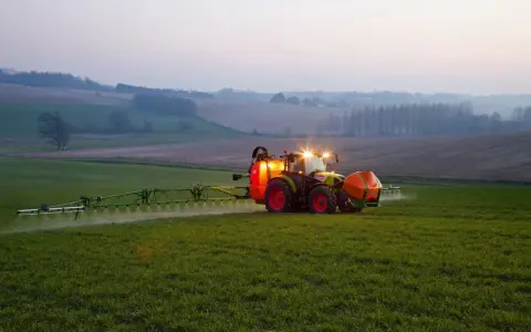 Ciągnik z opryskiwaczem na polu, precyzyjne dawkowanie roundup.