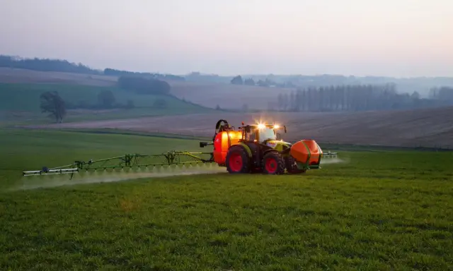 Ciągnik z opryskiwaczem na polu, precyzyjne dawkowanie roundup.